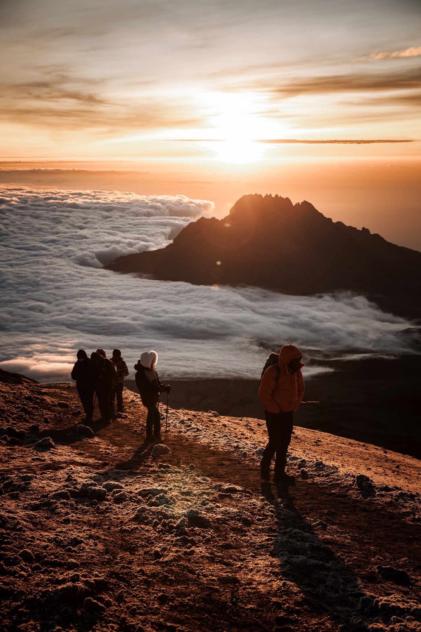 Climbers moving across a Kilimanjaro summit slope at sunrise.